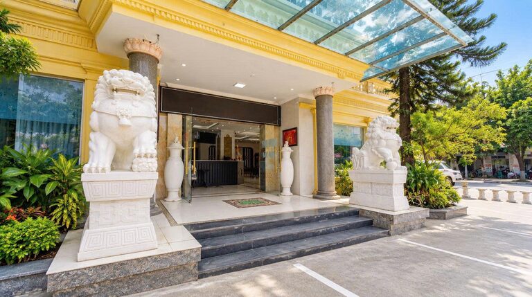 Cận cảnh lối vào sảnh khách sạn với bậc tam cấp, cột trụ và tượng sư tử đá hai bên