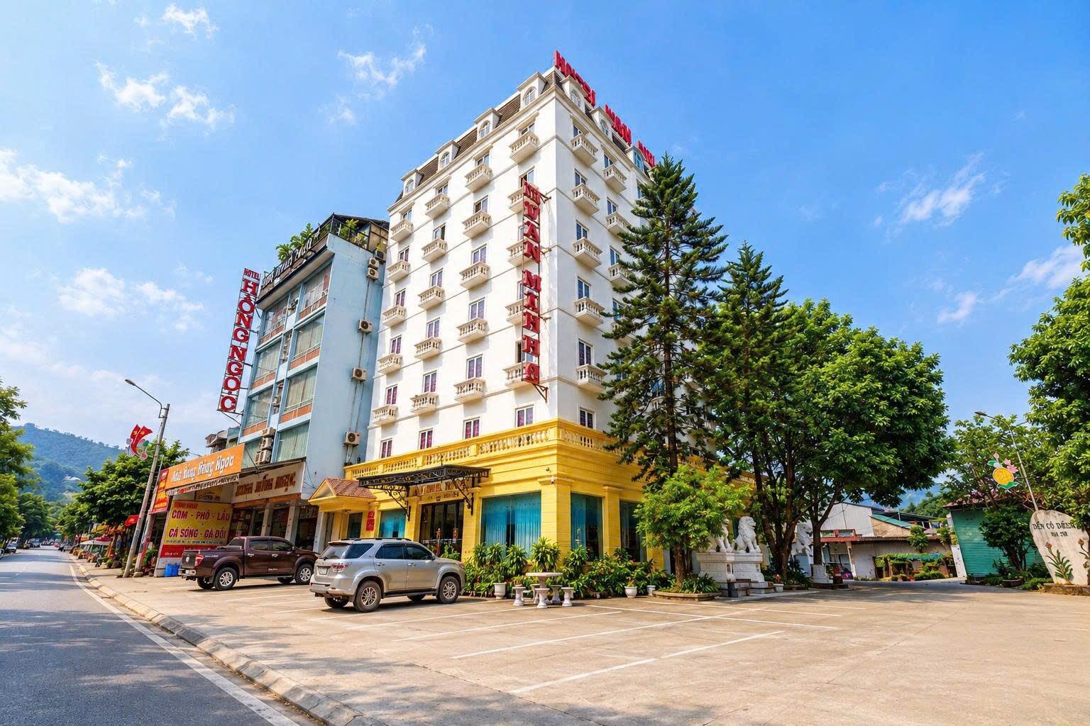 Toàn cảnh Khách sạn Văn Minh 2 nhìn từ đường, tòa nhà nhiều tầng sơn trắng và vàng dưới trời xanh