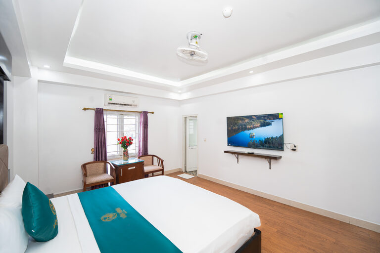 Góc phòng giường đôi với TV màn hình phẳng, góc bàn ghế và cửa sổ