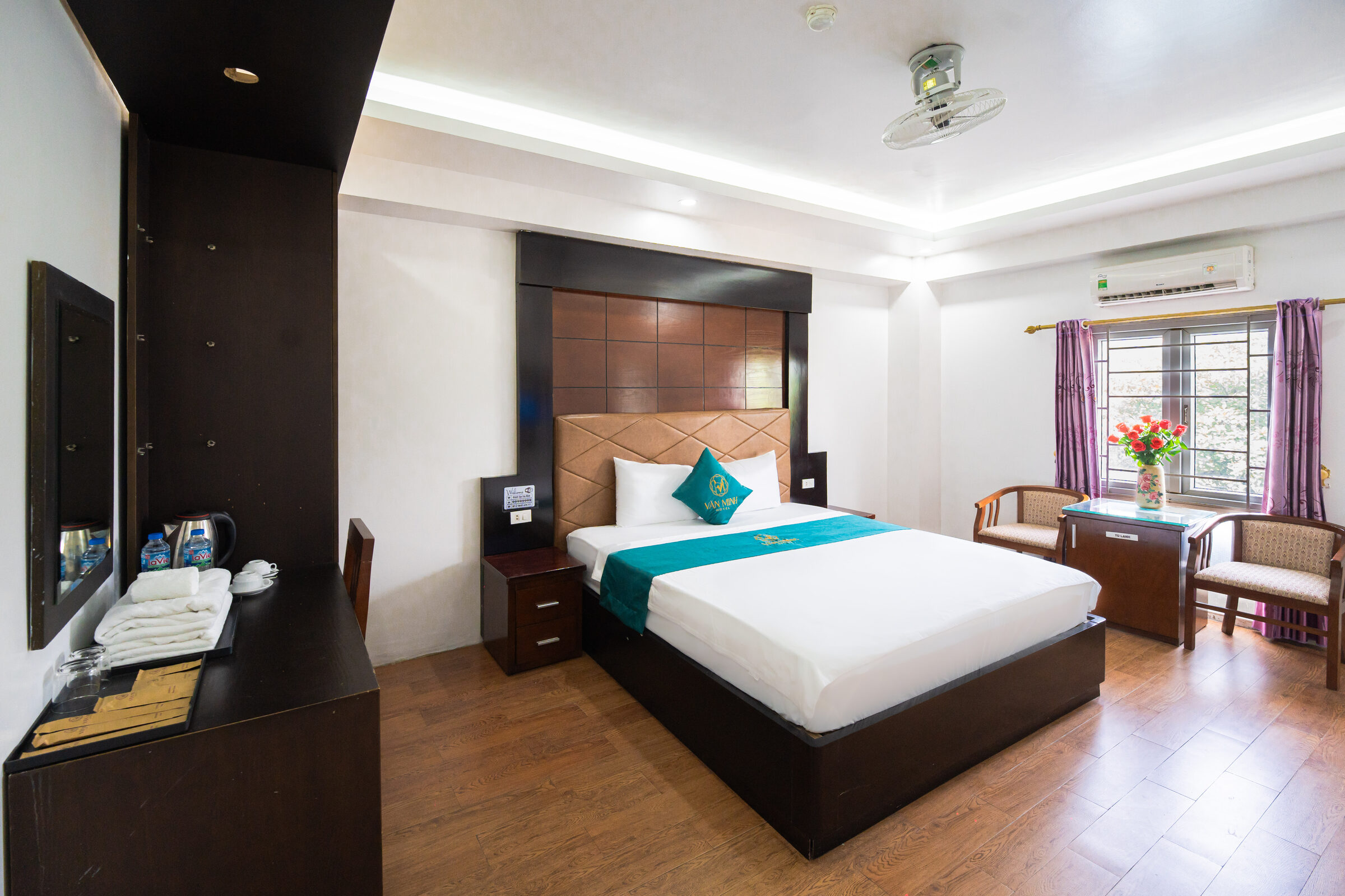 Toàn cảnh phòng giường đôi với điều hòa, quạt trần và cửa sổ nhìn ra cây xanh